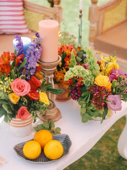 A sweet and colorful arrangement of roses and other blooms, accented with fresh oranges. The mix of colors and natural elements is perfect for a joyful daytime celebration.