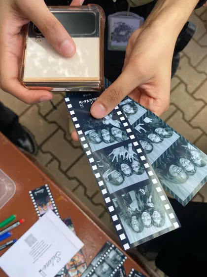 A close-up of someone holding their photo strips, showing the crisp quality of the black and white prints.