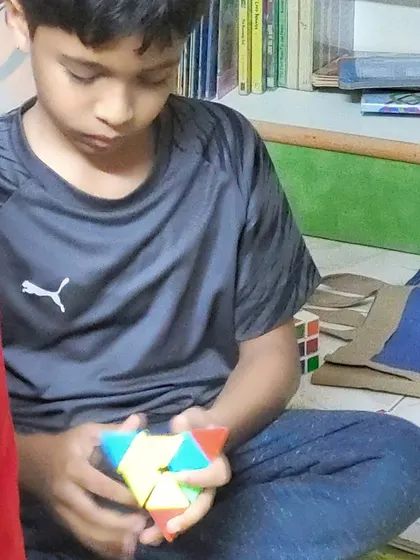 A close-up of a young member tackling a pyramid-shaped puzzle cube. We have a variety of puzzles to challenge different skill levels and keep young minds engaged.