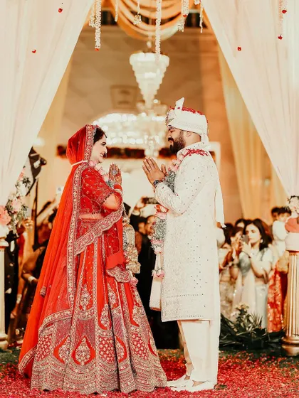 A classic moment of greeting at the start of the wedding ceremony, with the couple looking radiant under the warm lights of the mandap.