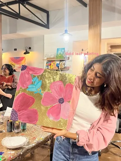 A guest proudly displaying her beautiful gold leaf painting. This technique adds a touch of elegance and shine to any artwork.