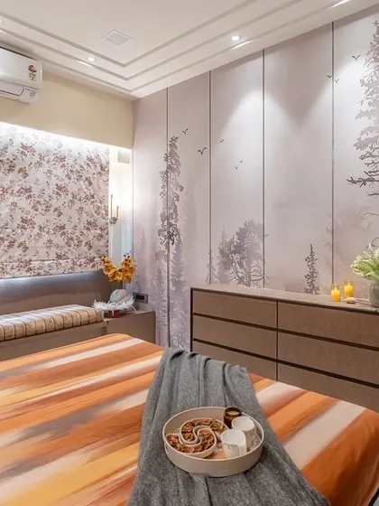 A view across the bed shows how the forest wallpaper and the floral window blinds bring elements of nature indoors. The long dresser provides ample surface space for decor and essentials.