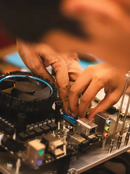 A detailed shot of hands working on a PC motherboard. This image captures the focus and precision that our students develop in our workshops.