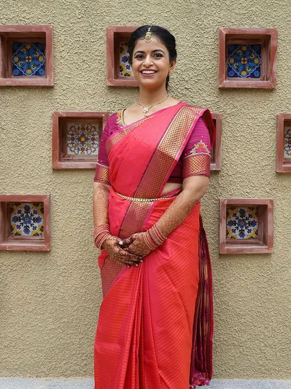 A beautiful bride in a pink saree, her hands adorned with a lovely, subtle henna stain for her special day.