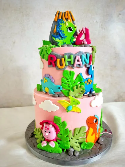 A two-tier pink dinosaur cake for a roaring 4th birthday celebration.