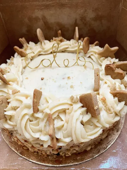 A top-down view of a custom cake for a pup named Caleb, ready to be packed. It's decorated with fluffy frosting and lots of little homemade biscuits.