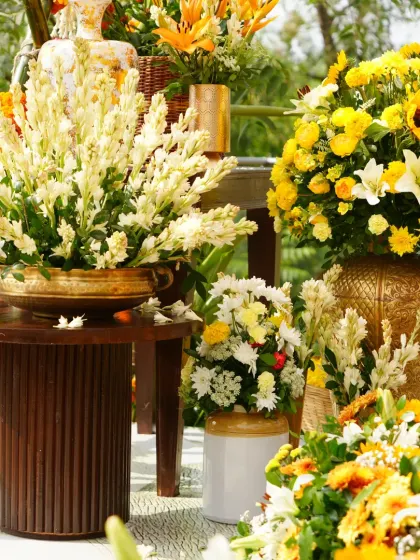 A beautiful composition of floral arrangements on rustic wooden tables, showcasing the rich textures and colors of the Haldi decor.