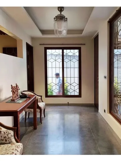 An interior view of a hallway with cool concrete floors and warm wooden furniture.