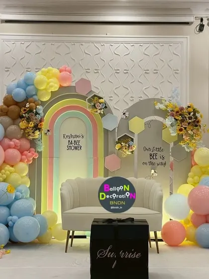 A vibrant and colorful baby shower combining a rainbow arch with a "little bee is on the way" theme, showing how we can merge ideas.