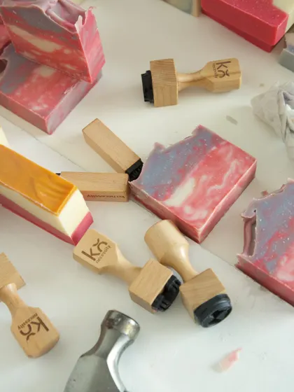 A collection of my soap stamps alongside freshly stamped bars. These little tools help me add a special, personal touch.