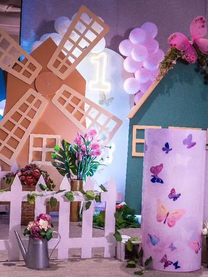 A whimsical butterfly garden theme featuring a charming windmill, a mushroom house, and oversized butterfly wings. This setup creates a storybook scene for a child's birthday party.