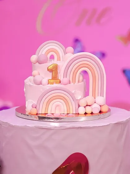 A beautiful two-tiered cake for a first birthday, decorated with pastel rainbows and delicate butterflies. This cake was the centerpiece of a whimsical and elegant celebration.
