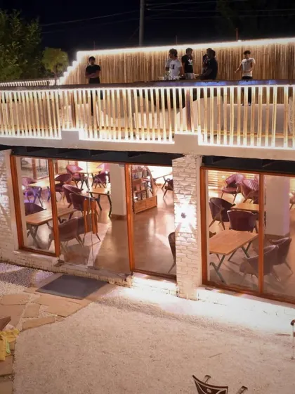 A view of the indoor cafe from the outside, with guests enjoying their time on the rooftop terrace above.