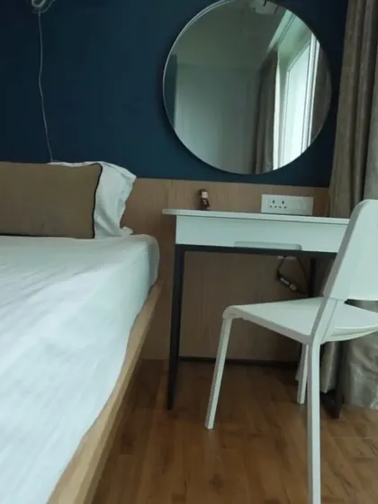 This image shows a compact study or vanity table integrated next to the bed. The sleek, handle-less drawer and metal legs complement the modern aesthetic of the room.
