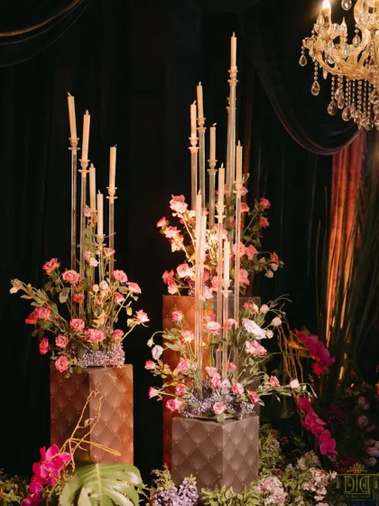 Tall, modern candelabras paired with soft pink floral arrangements added a touch of contemporary elegance to the masquerade sangeet. The contrast between the dark, moody drapes and the delicate flowers created a visually stunning effect.