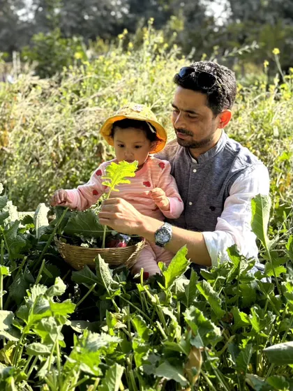 A father and his young child sit amongst the lush green plants, a peaceful moment of connection between family and nature.