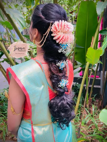 A modern wavy braid hairstyle for a housewarming event. The use of colorful flowers and a side hair accessory makes this a fun and festive look.