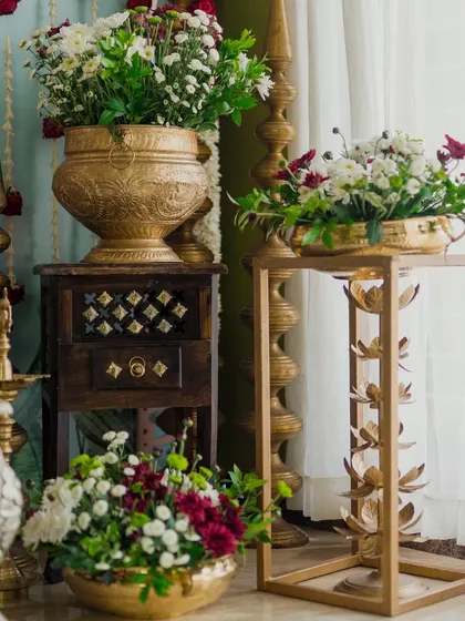 Traditional decor elements like these ornate brass pots and stands, filled with fresh flowers, add a touch of cultural richness and elegance to any event space.