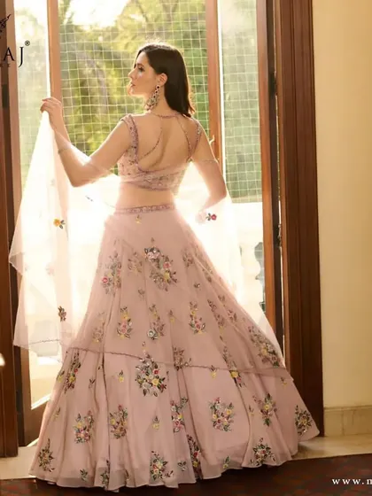 The back view of the pink floral crop top lehenga, showcasing its delicate design and angel sleeves.