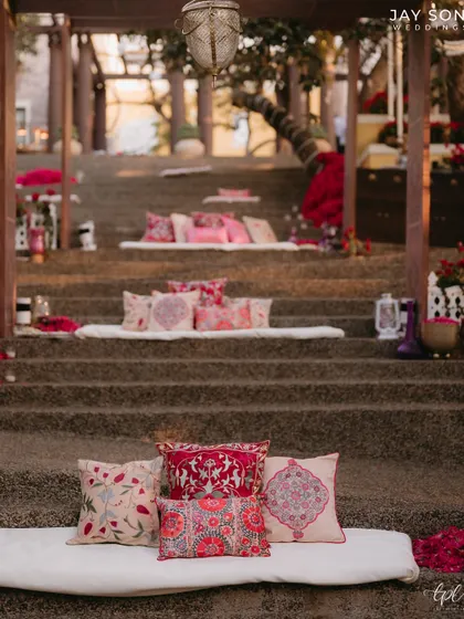 Unique tiered seating for the Mehfil-e-Mehendi, where mattresses and vibrant cushions are placed on stone steps, creating a relaxed and communal amphitheater-style lounge.