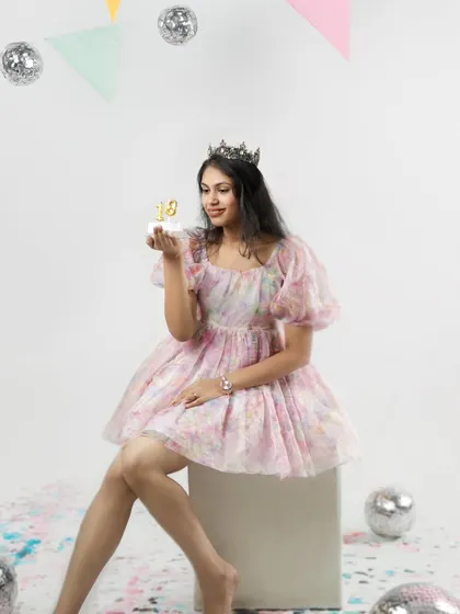 A princess for a day. Wearing a crown and holding a small cake, she looks elegant and happy as she celebrates turning eighteen.