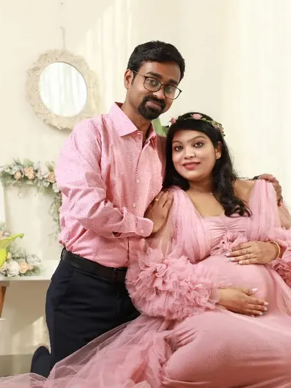 A sweet couple portrait in my studio's lifestyle corner. The mom-to-be is radiant in a pink ruffled gown, creating a dreamy and romantic atmosphere for their maternity shoot.