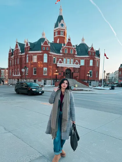 Capturing the winter magic in Stratford, Ontario. This shot shows how I style a cozy but chic winter outfit with a plaid long coat and scarf against a beautiful, historic backdrop.