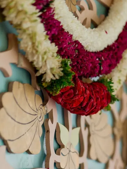 A close-up of a traditional floral garland against a custom-carved backdrop. This image highlights the texture and craftsmanship that go into our decor.