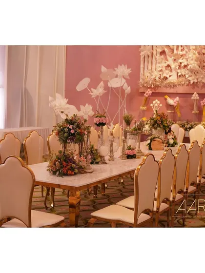 An overview of a pretty pastel tablescape. The combination of a marble-topped table, elegant scalloped chairs, and delicate floral arrangements creates a sophisticated and romantic dining atmosphere.