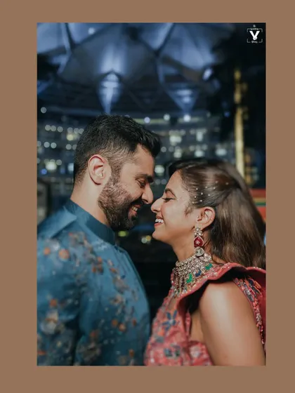 A vibrant, moody portrait of a couple smiling at each other, nose-to-nose, against a beautifully lit architectural background at night. This shot showcases our skill in creating stunning nighttime couple portraits.
