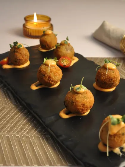 A platter of my Arancini Balls, elegantly plated on a slate board with a drizzle of sauce. The presentation is just as important as the taste.