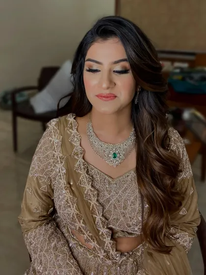 A soft and romantic look for an evening function. The makeup features a gentle smokey eye and loose waves, perfect for her elegant beige and green outfit.