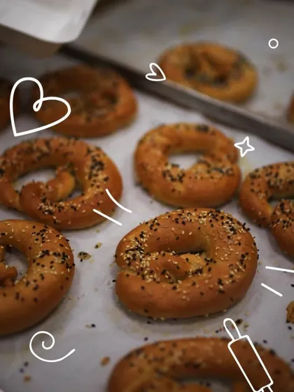 A tray of freshly baked pretzels, golden brown and sprinkled with seeds. Learning the unique twisting technique is one of the highlights of our bread workshop.