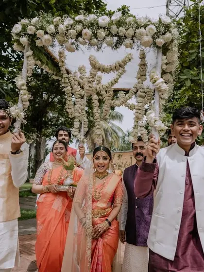 The bride's joyful entrance under a phoolon ki chadar. This shot captures the happiness of the bride and her family as they walk towards the mandap.