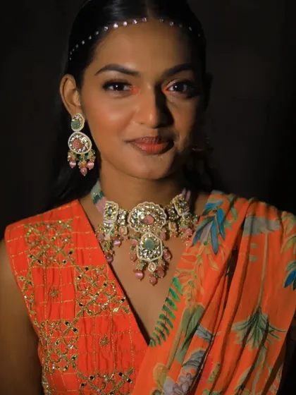 A model showcasing a unique pastel choker set against a vibrant orange outfit. This shows how I can create custom pieces that stand out and complement your attire.