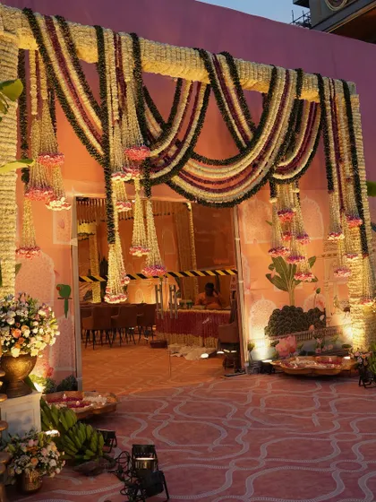 The entrance to the celebration, framed by a massive archway of woven tuberose and draped with heavy garlands of marigolds and roses. This grand entrance sets a festive and welcoming tone.