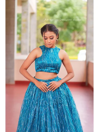 A front view of the model in the teal lehenga, showing the textured, shimmering fabric of the skirt and top.