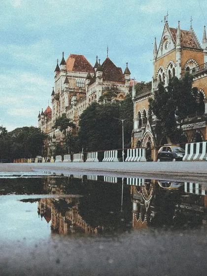 A puddle reflection of the historic buildings near the Bombay High Court, a creative angle that captures the city's beauty.