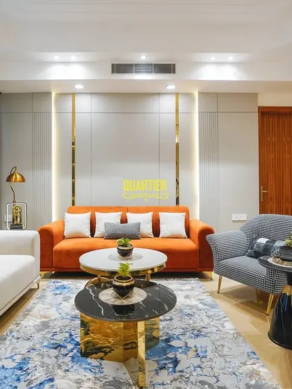 This wide shot of the Apex D'Rio living room shows how I balance bold furniture choices with a neutral wall color. The grey paneled walls with gold strips add texture and sophistication without overwhelming the space.