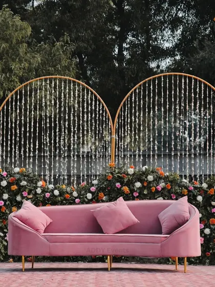 A closer look at the pink velvet sofa against the floral and decorative backdrop. This seating is not only comfortable for the couple but also adds a pop of contemporary color and style to the stage.