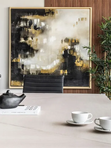 We love playful asymmetry in a professional setting. Here, a large abstract artwork is hung off-center, overlapping the wall and wood paneling to create a dynamic focal point in the conference room.
