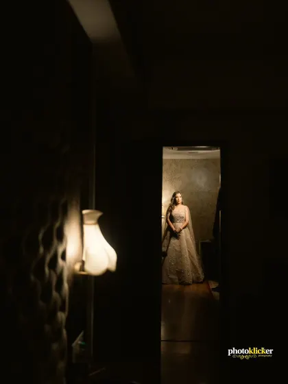 An artistic, low-light shot of the bride-to-be, framed by a doorway, creating a sense of anticipation and drama.