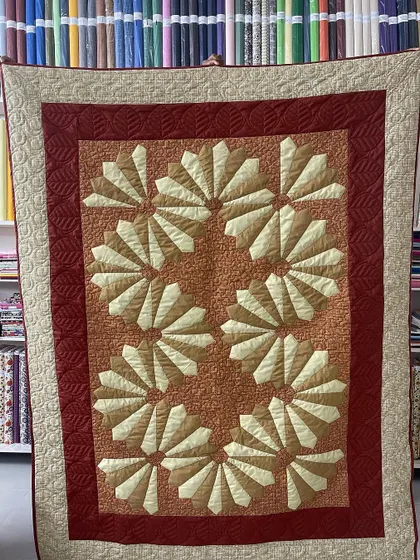 A "Dresden Plate" quilt in warm, earthy tones of orange and red. This classic pattern is known for its beautiful, fan-like blocks.