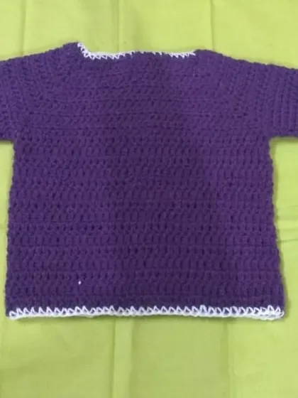 A simple purple crochet baby t-shirt with a clean white trim along the edges.
