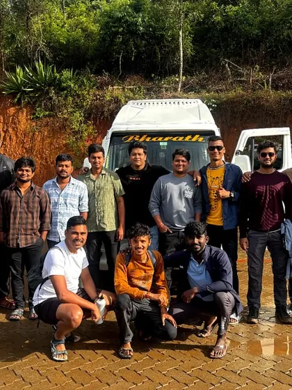 A group poses with their tempo traveler, ready to head out. The journey starts here.