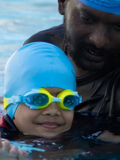 A coach provides gentle support and verbal encouragement to a young swimmer. This personal attention helps build trust and accelerates learning.