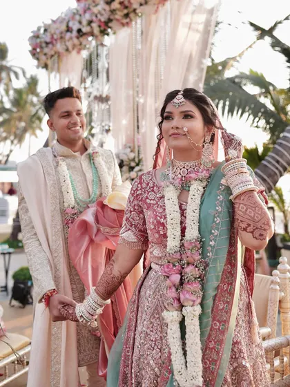 A candid moment from a beautiful beach wedding. The bride's pastel lehenga is paired with soft, romantic makeup that looks flawless in the sun.