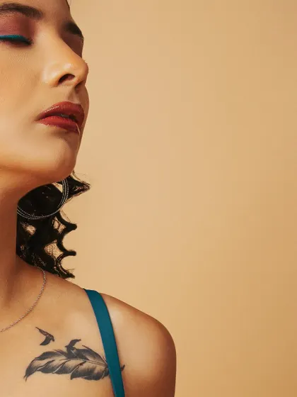 A serene, artistic beauty portrait focusing on the model's profile and a hint of her shoulder tattoo.
