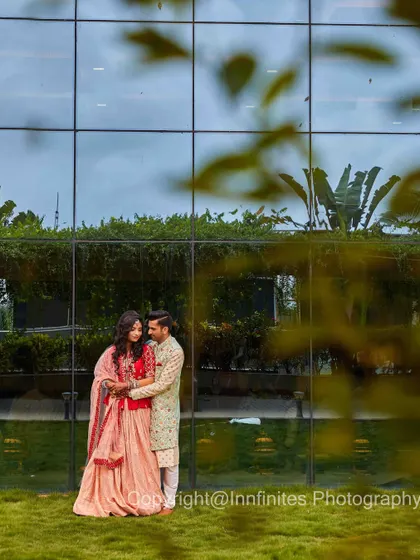 A modern and stylish engagement portrait against a glass-paneled building, capturing the couple in a loving embrace.