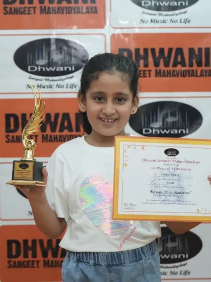 A young girl proudly holds her certificate and trophy.